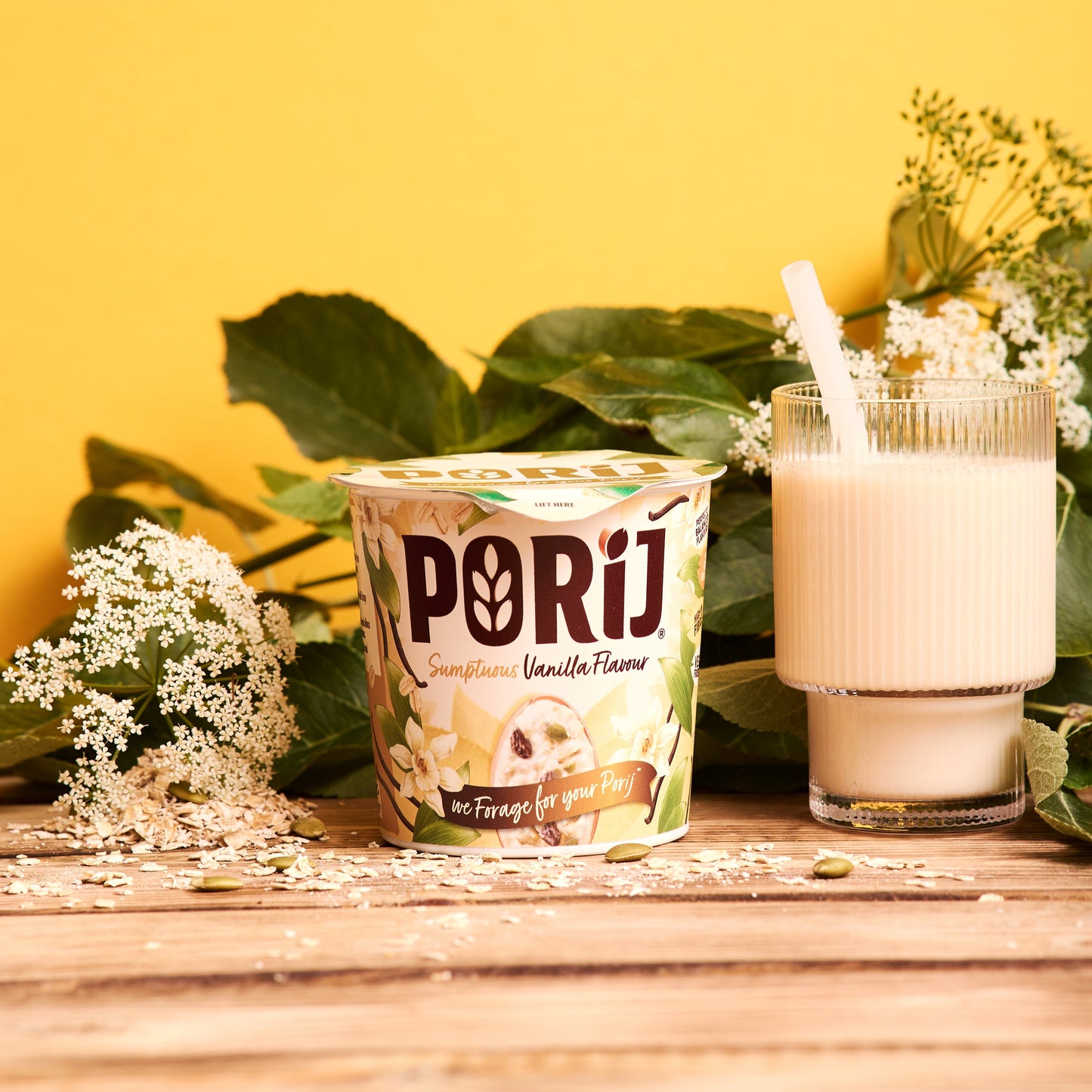 Porij Porridge container with a glass of milk on a wooden surface with greenery in the background